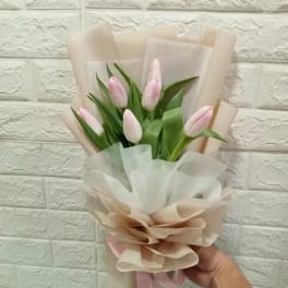 Bouquet of pale pink tulips wrapped in beige and white paper