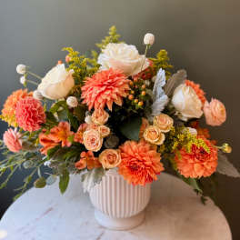 Bouquet of peach and white flowers in a ribbed white vase