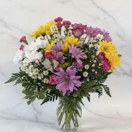 Mixed bouquet of daisies and roses in a clear glass vase