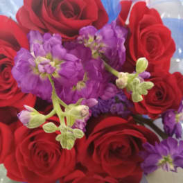 Bouquet of red roses and purple flowers wrapped in blue paper