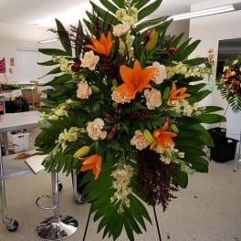 Tall standing floral spray with orange lilies and pale carnations