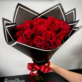 Bouquet of red roses wrapped in black paper with a red ribbon