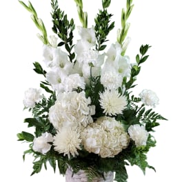 White floral arrangement with gladiolus, hydrangeas, carnations, and mums in a basket