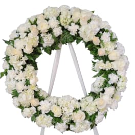 White floral wreath on a stand with roses and hydrangeas