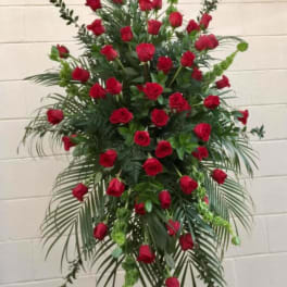 Tall standing arrangement of red roses with greenery