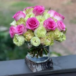 Pink and pale green roses arranged in a glass vase