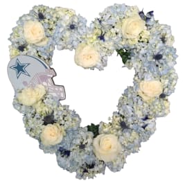 Heart-shaped floral arrangement with pale blue and white flowers and cream roses