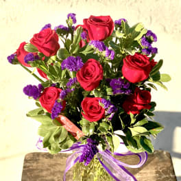 Bouquet of red roses and purple filler flowers in a glass vase