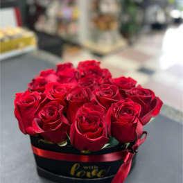 Red roses arranged in a black hat box with a red ribbon