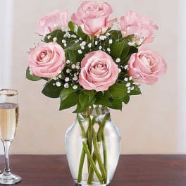 Pink roses arranged in a clear glass vase with baby's breath