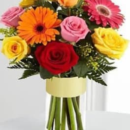 Mixed bouquet of roses and gerbera daisies in a clear glass vase