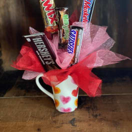 Candy bars arranged in a heart-pattern mug with pink and red tissue paper