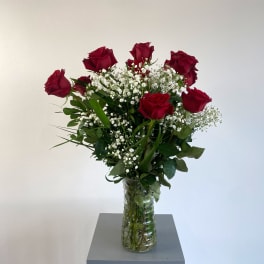Red roses in a clear glass vase with baby's breath