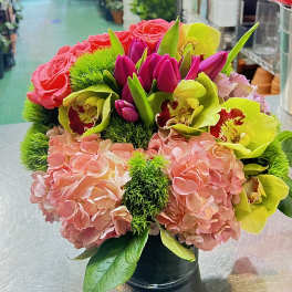 Bouquet of pink hydrangeas, roses, and lime orchids in a black vase