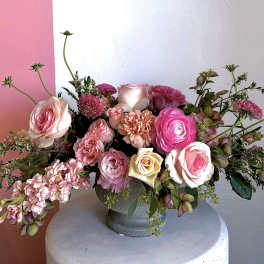 Pink and cream rose arrangement in a gray vase
