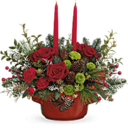 Red roses and candles in a low holiday centerpiece with pinecones