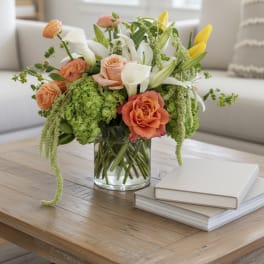Mixed bouquet of roses, calla lilies, and yellow tulips in a glass vase
