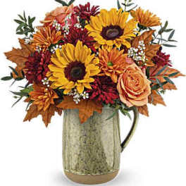 Autumn bouquet of sunflowers, roses, and mums in a metal pitcher