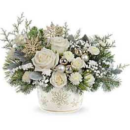 White roses and winter greenery in a snowflake vase