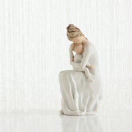 A white figurine of a seated woman holding a child