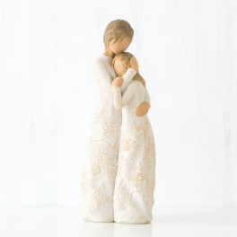 Two carved figurines in white dresses embracing