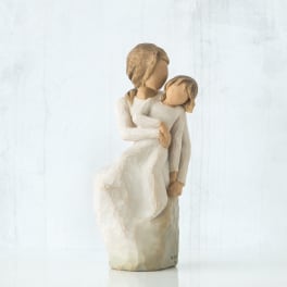 Carved figurine of an adult holding a child in cream tones