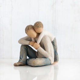 Two faceless figurines sitting close together in an embrace