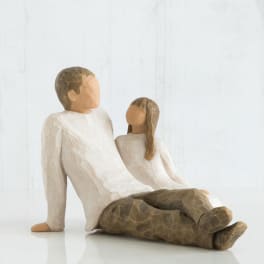 Two carved figurines of a seated man and woman in neutral tones