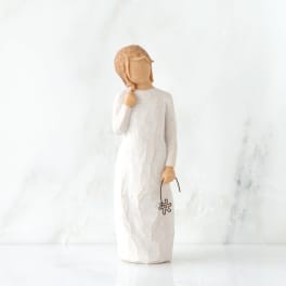 Wooden figurine of a girl in a white dress holding a small flower