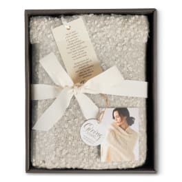 Folded cream knit shawl in a gift box with ribbon and tags