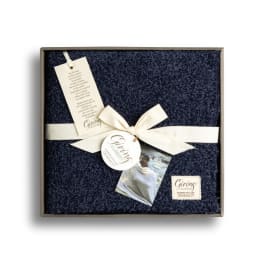 Gift box with a navy textured blanket tied with a cream ribbon