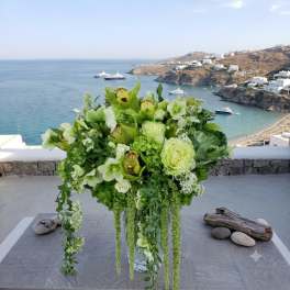 Green and white floral arrangement in a clear glass vase with trailing stems