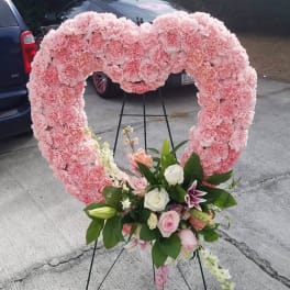 Large pink heart-shaped floral wreath with a small mixed bouquet at the bottom