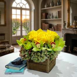 Yellow roses and green orchids in a square burlap-covered box