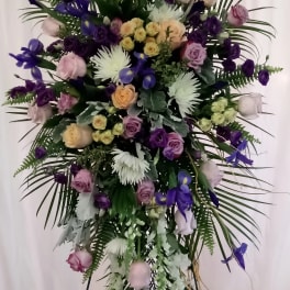 Tall floral standing spray with purple, white, and blush blooms