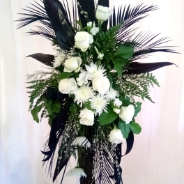 White floral standing spray with dark foliage on a stand