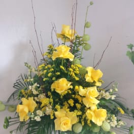 Tall arrangement of yellow roses with white flowers and green accents