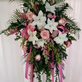 Standing floral spray with white lilies and pink roses on a pink ribboned easel