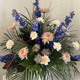 Tall floral arrangement with blue and peach blooms in a vase
