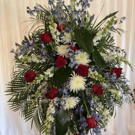 Tall standing floral spray with red roses, white blooms, and blue flowers
