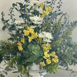 White and yellow flowers in a white pedestal vase