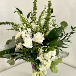 White roses and hydrangeas in a glass vase with mixed greenery