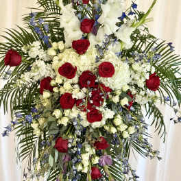 Tall floral standing spray with red roses, white blooms, and blue accents