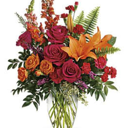 Bouquet of orange lilies and pink roses in a clear glass vase