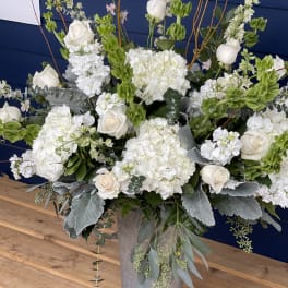 White roses and hydrangeas in a tall metal vase