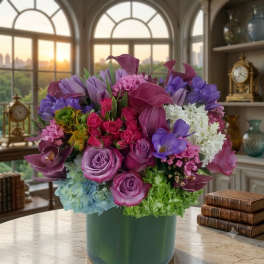 Mixed bouquet of purple, pink, and white flowers in a green vase