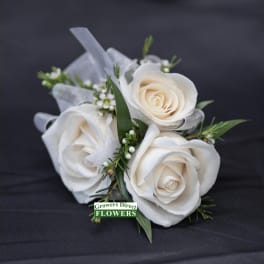 Three white roses with small filler flowers and ribbon