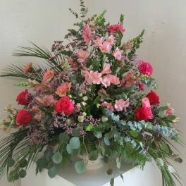 Large pink and red floral arrangement in a white vase