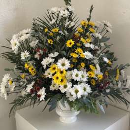 White and yellow daisy arrangement in a white vase