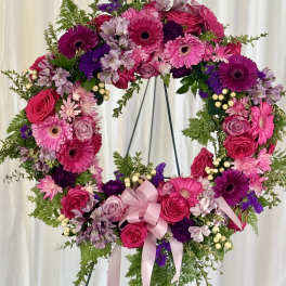 Heart-shaped floral wreath with pink and purple flowers on a stand